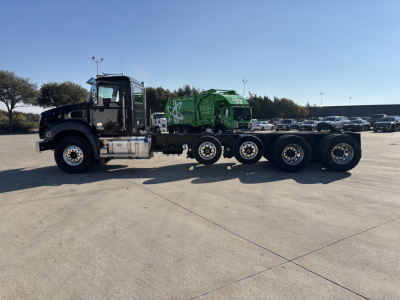  Mack GR64B cab and chassis truck with green waste truck in the trailer showing side view and 6-wheel rear axle.