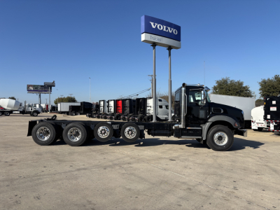 2025 Mack GR64B cab and chassis truck side view showing multiple axles and Volvo Trucks sign in lot.
