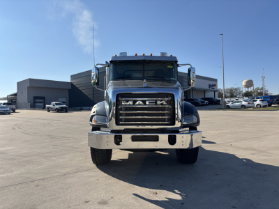 Front view of a 2025 Mack GR64B cab and chassis showing prominent grille with 'MACK' lettering, chrome bumper, dual headlights, and cargo area behind cab.