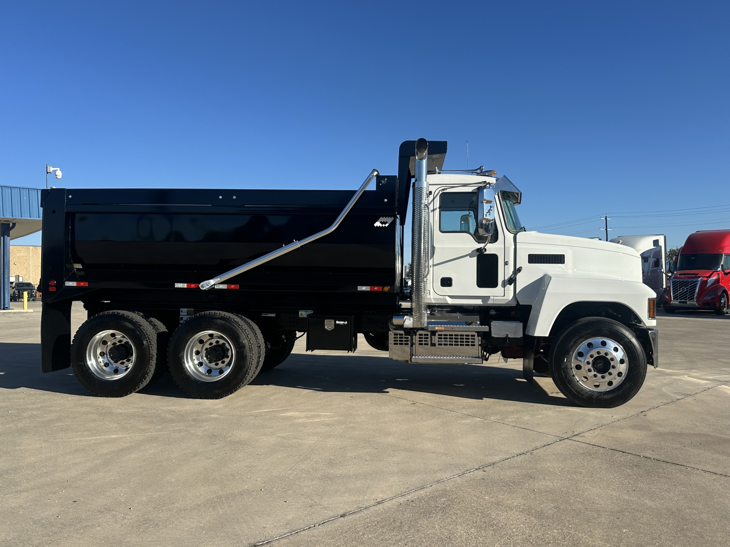 Mack PI64 dump truck side view showing black dump body and white cab.