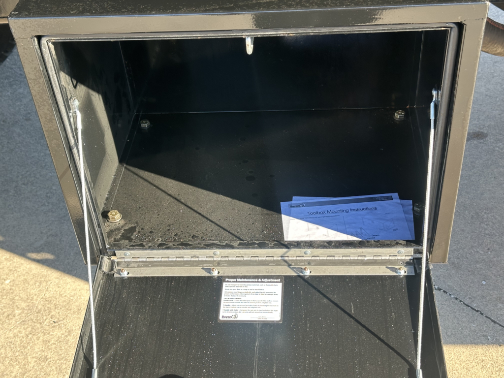 Truck dump body box open showing empty cargo interior with a small stack of papers at the bottom.