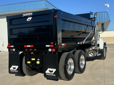 Dump truck rear and side view showing a black Mack PI64 dump truck with Warren logo mud flaps and dual rear axles, bed raised slightly.