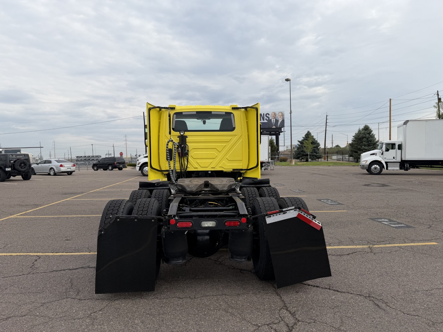Truck cab rear view of 2023 International LT625 with yellow sleeper and dual rear axles in a dealership lot.