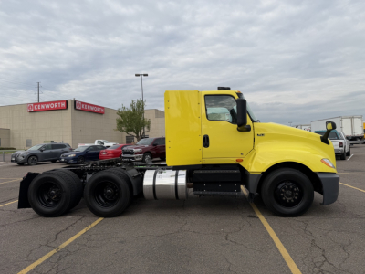 Yellow International LT625 daycab tractor shown in side profile with triple rear axles and fuel tanks.