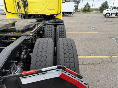 Tractor-trailer rear wheels and chassis showing dual rear axles and fifth wheel mounting on a yellow cab.
