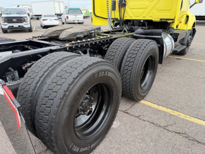 Pair of dual rear truck tires on a yellow 2023 International LT625 tractor showing wheel rims and frame.