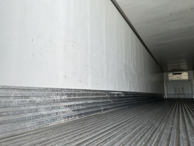 Trailer interior showing empty reefer trailer with ribbed aluminum floor and sidewalls, open rear door, long rectangular cargo bay.