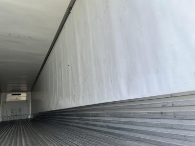 Trailer interior showing corrugated metal floor and side walls of a reefer trailer.