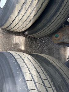 Rear view of a trailer axle with dual tires showing tread and sidewall details; no license plate visible.