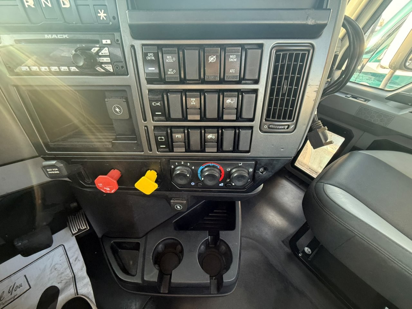 Dashboard of a 2020 Mack PI64T truck showing toggle switches, climate controls, and cup holders in center console.