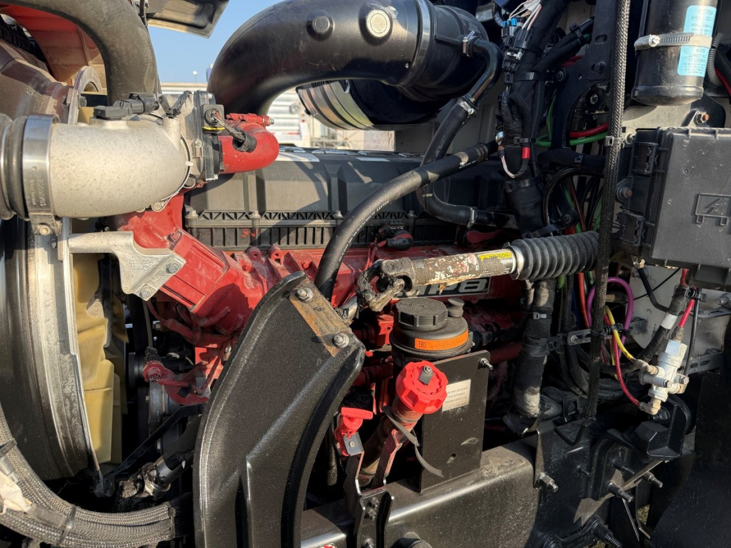 Mack PI64T engine bay showing diesel engine components with red air filter housing, hoses, and various labels.