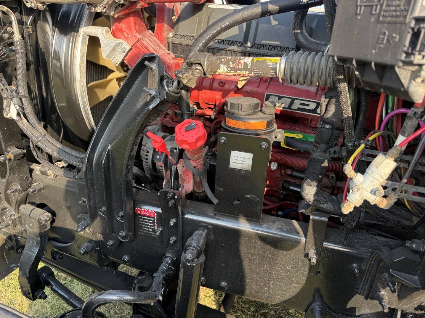 Mack PI64T engine bay showing coolant reservoir and various hoses and components.