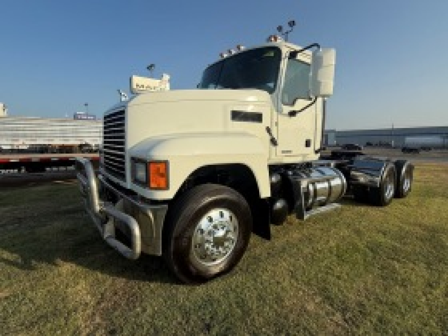 Front-left view of a 2020 Mack PI64T truck with a large white cab, chrome bumper guard, dual rear axles, and fuel tanks visible on the side.