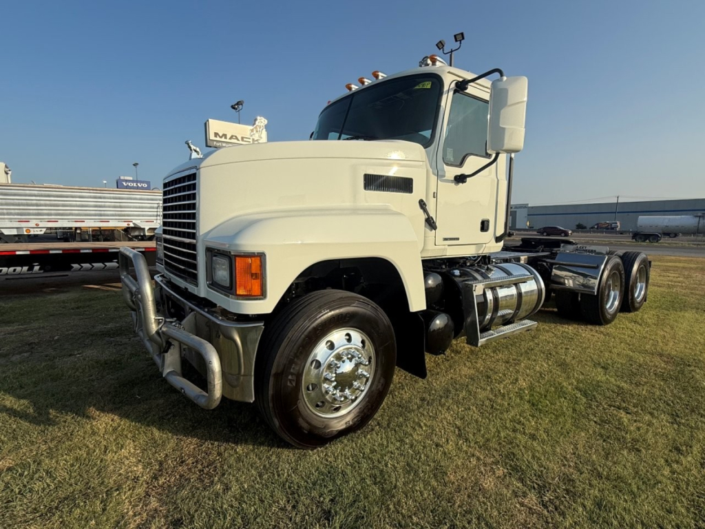 2020 Mack PI64T conventional daycab truck on grass, front-left angle showing chrome bumper guard, dual rear axles, fuel tanks, and large side mirrors.