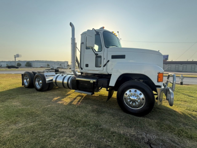 Truck cab and chassis of a 2020 Mack PI64T conventional daycab showing side profile with dual rear axles and fuel tanks.