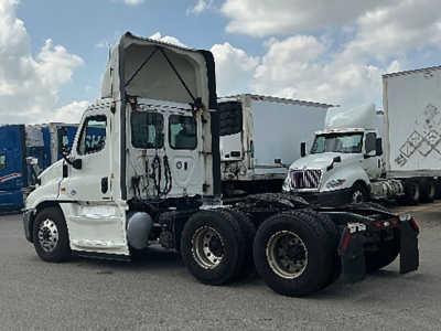 Truck tractor cab and chassis of a 2019 Freightliner Cascadia Evolution, white exterior, daycab configuration, with sleeper area raised, dual rear axles, nearby trucks.