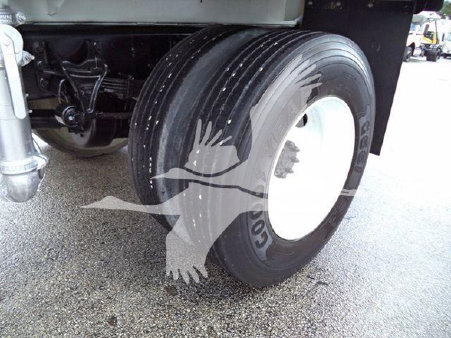 Truck wheel and front suspension of a 2015 Ford F650 with large rear dual tires, white wheel hub, black frame, and mudguard.