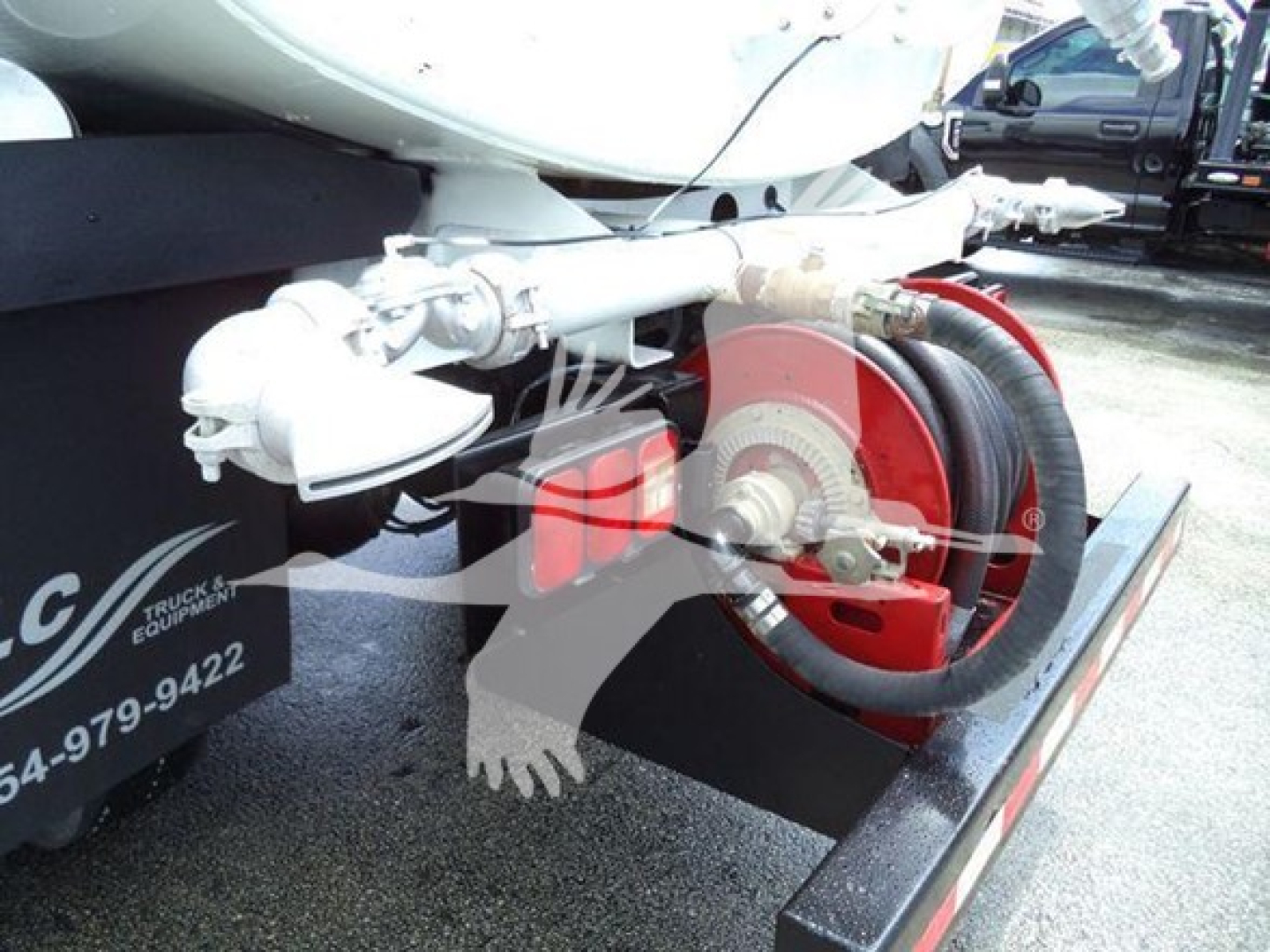 Tractor-trailer hitch and hose reel on a Ford F650 dump truck chassis showing a red coil hose reel and metallic piping mounted to a trailer with a black mudguard.