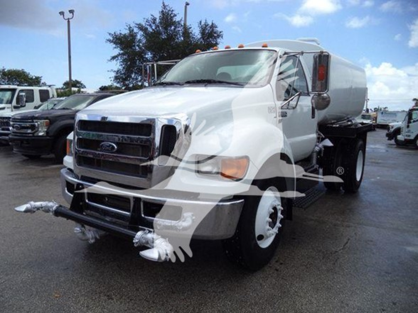 Ford F-Series truck with water tank body showing front grille, headlights, and metallic white tank; cab and bumper visible.