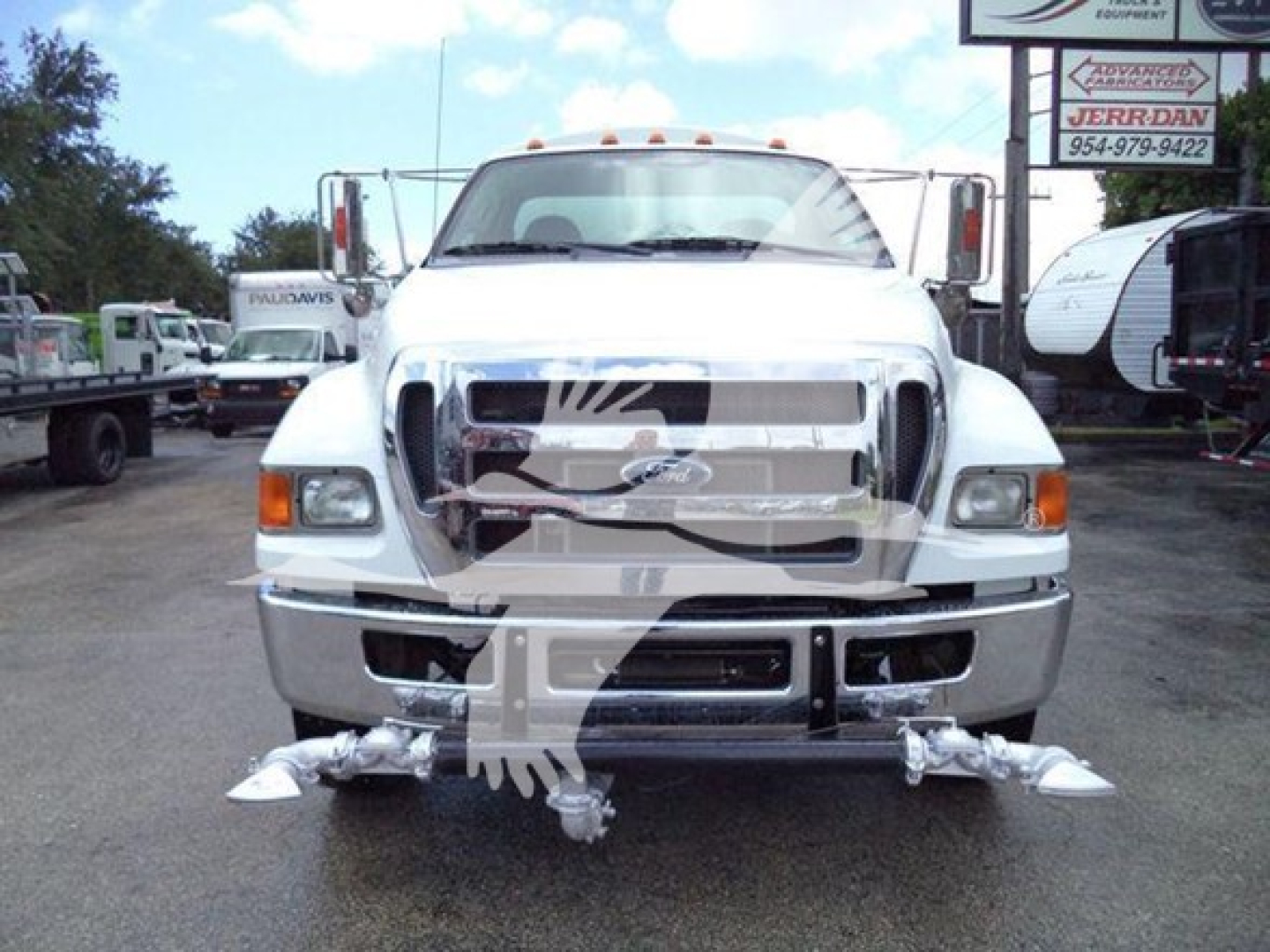 Front view of a white 2015 Ford F650 SD truck showing chrome grille, bumper, and underride guard with accessories and fog lights.