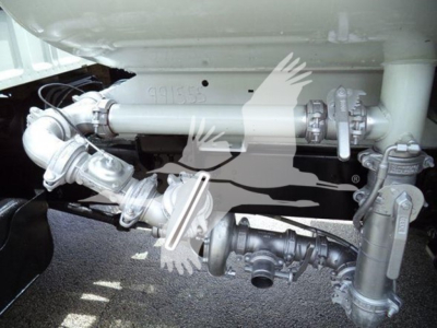 Trucks equipment section showing plumbing/piping and valve assemblies under a Ford F650. Visible components include metal pipe, fittings, valves, and a black plastic hose/valve assembly with clamps.
