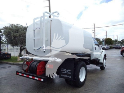 Ford F650 water truck in-service showing tank and rear hose reel assembly with white body and red hose reel.
