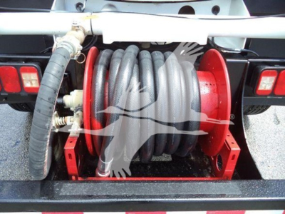 Winch reel mounted to rear of Ford F-650 truck with coiled hose/wire on spool and red frame.