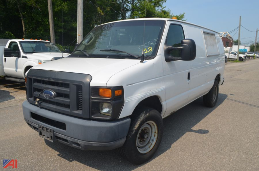 Ford E-Series cargo van showing front grille, headlights, and side profile with cargo conversion windows