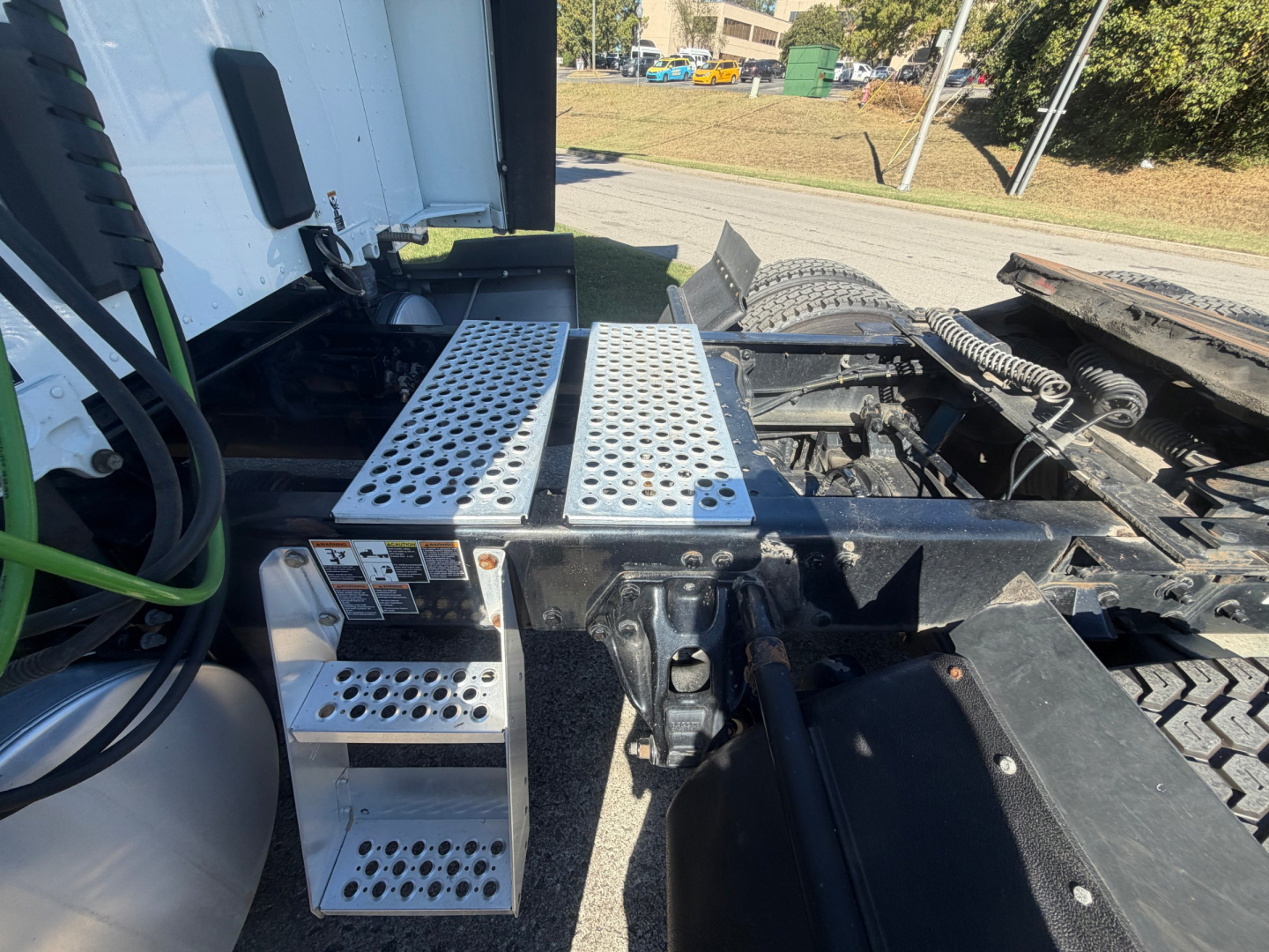 Kenworth T680 chassis area showing perforated aluminum steps and access platforms with black metal frame and tire in background.