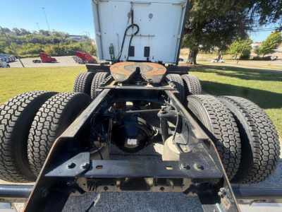 Kenworth T680 chassis rear view showing fifth wheel, dual rear axles, air lines, and drivetrain components with visible frame rails and suspension.