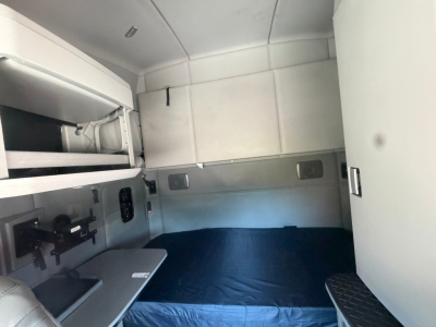 Kenworth T680 sleeper cab interior showing bunk bed area and storage compartments.