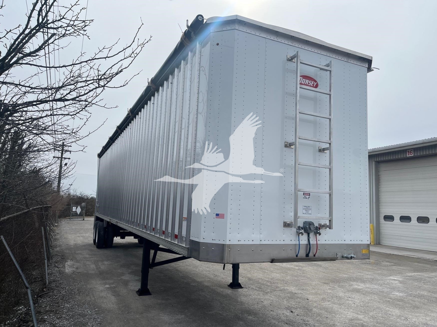 Dorsey walking floor trailer side view showing 2027 model with hitch, landing gear, side ladder, and eagle decal on aluminum surface.