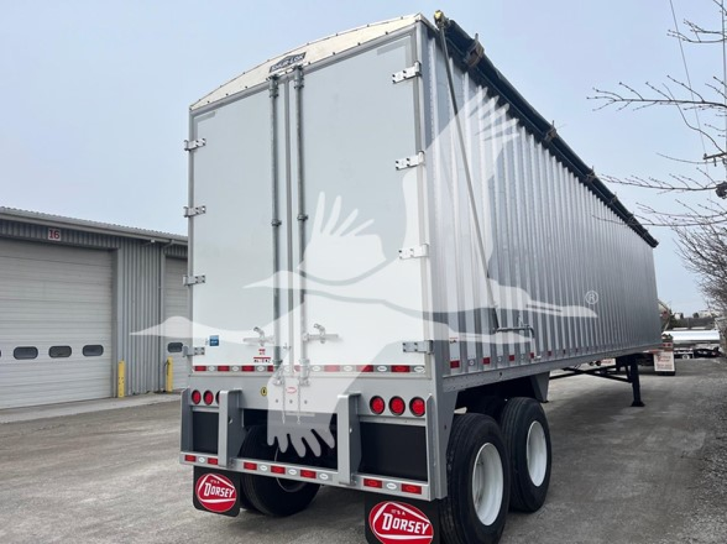 Dorsey walking floor trailer rear and side view showing gray aluminum body with doors, dual rear axles, mud flaps with Dorsey logo, and queen-style landing gear.