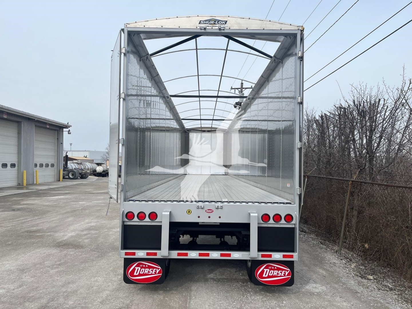 Dorsey walking floor trailer in-yard rear view showing open cargo area, tail lights, and Dorsey mudflaps.