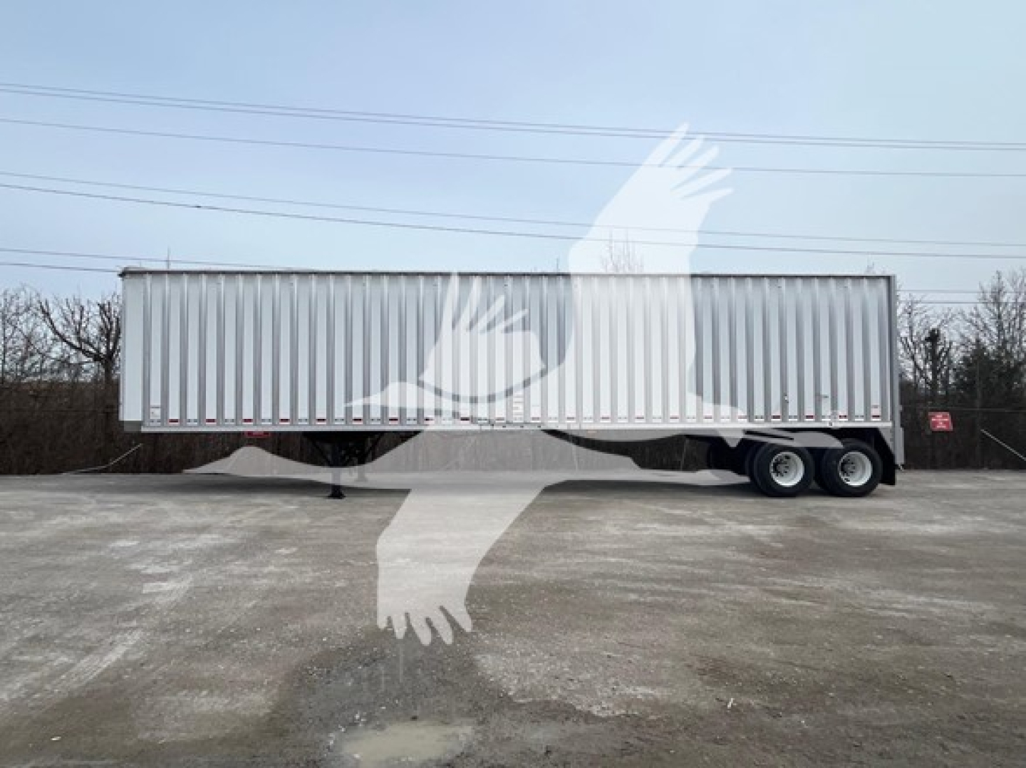 Trailer side view showing Dorsey walking floor trailer with tandem axles and side paneling.