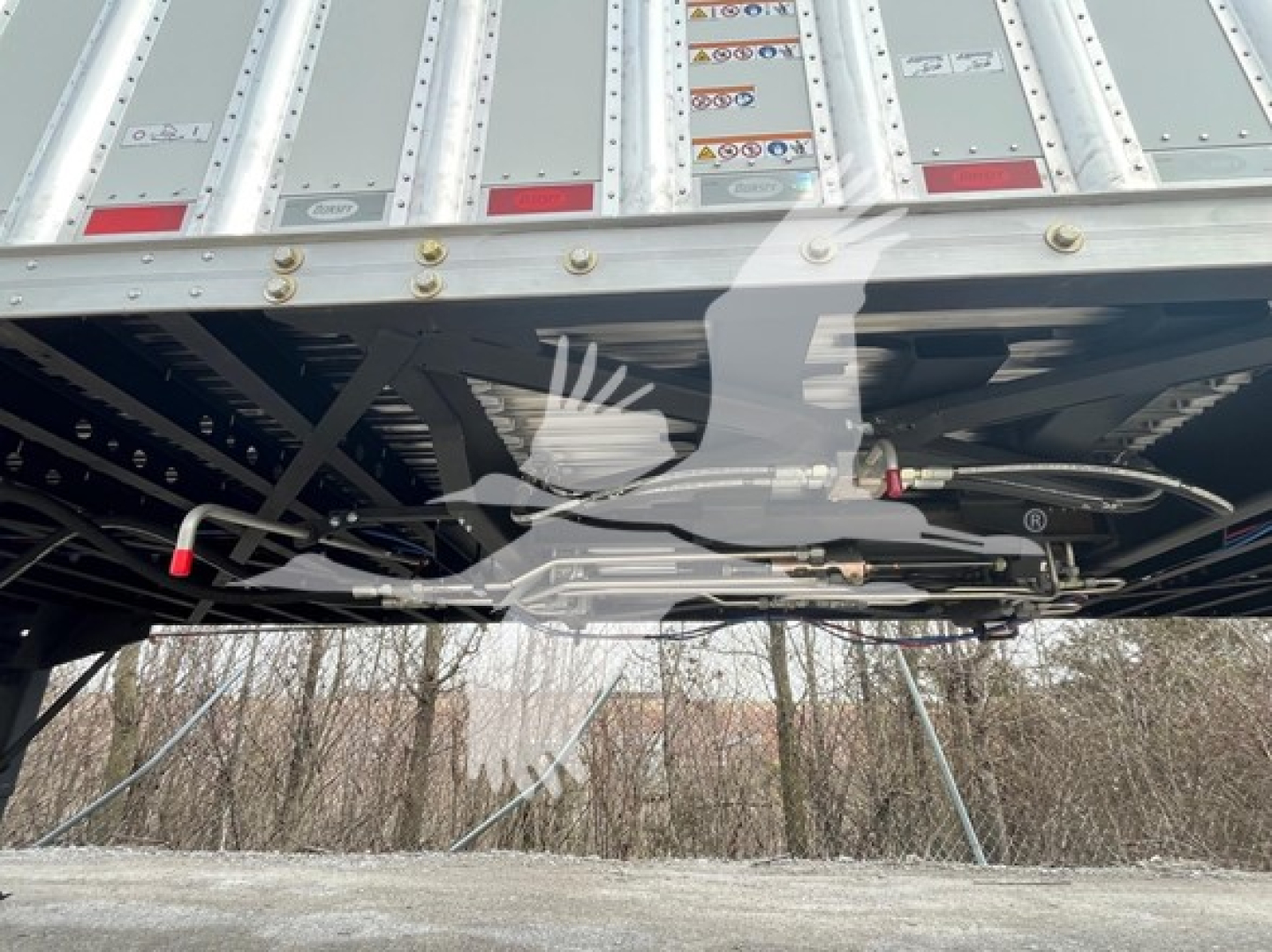 Dorsey Walking Floor trailer underside view showing frame rails, hydraulic lines, and bolts with reflective tape.