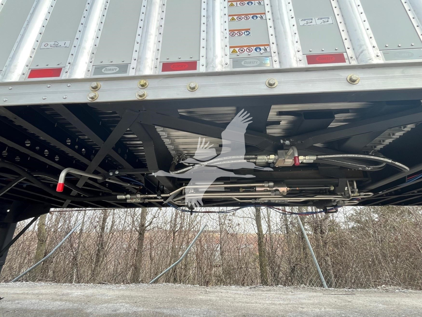 Trailer undercarriage showing walking floor mechanism and hydraulic lines beneath a Dorsey trailer.