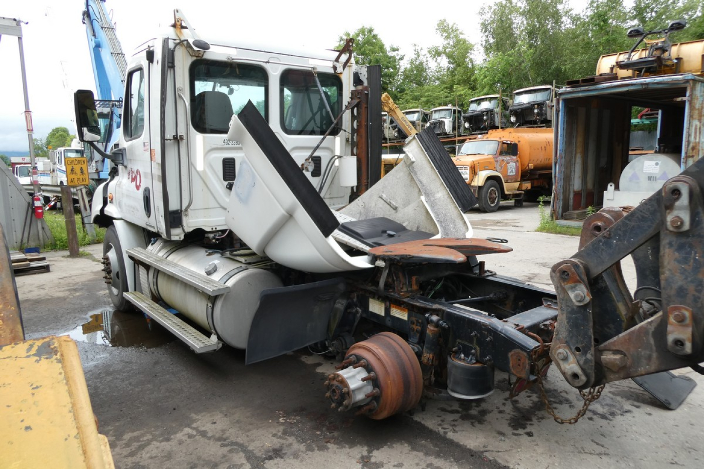 Truck cab and rear section of a Freightliner Cascadia 113 with damaged wheel hub and exposed drive components.