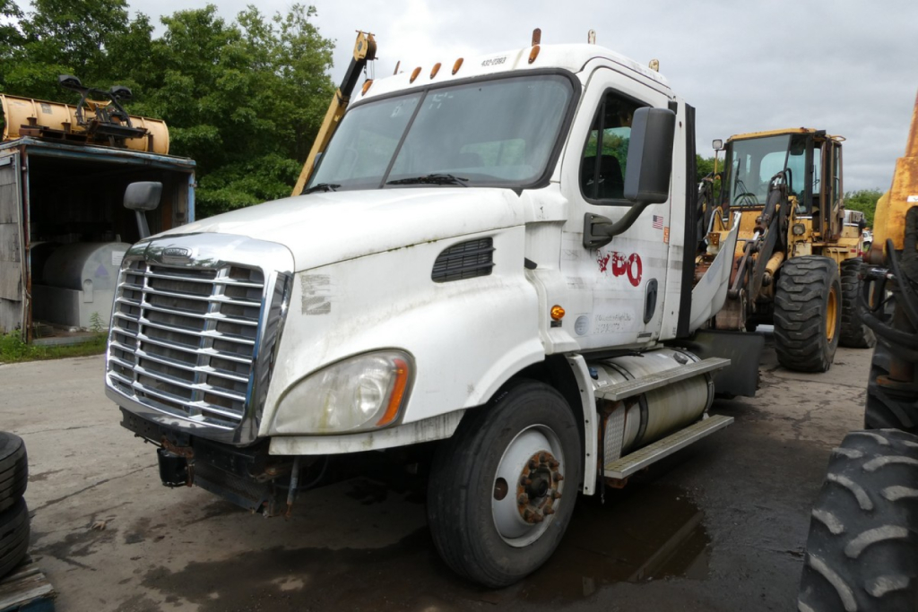 Truck cab with white Freightliner Cascadia 113 daycab showing front grille and side fuel tanks