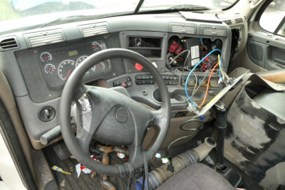 Dashboard and steering wheel inside Freightliner Cascadia cab showing exposed wiring and dashboard components.