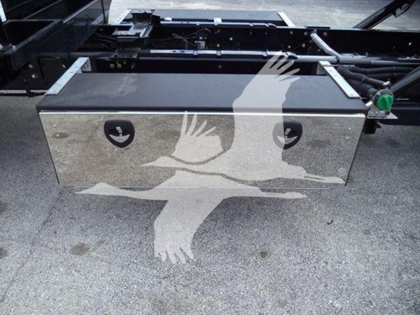 Toolbox mounted under the chassis of a 2023 International CV truck rollback showing a metal storage box with two circular access panels.