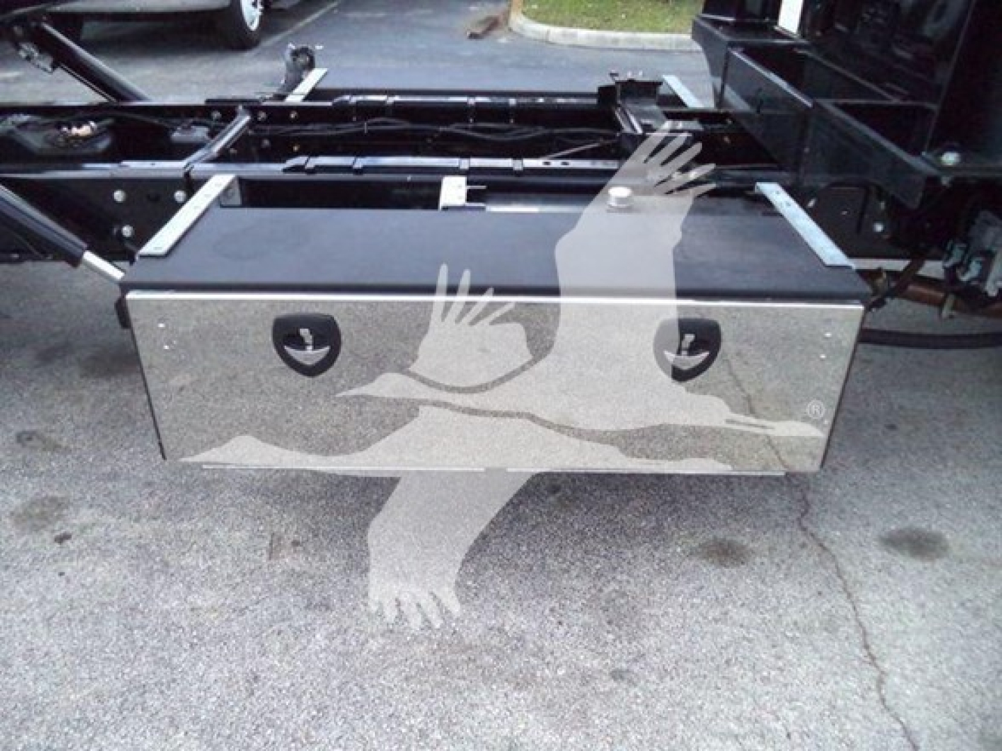 Aluminum toolbox mounted under a truck chassis with pneumatic hoses and frame components visible.