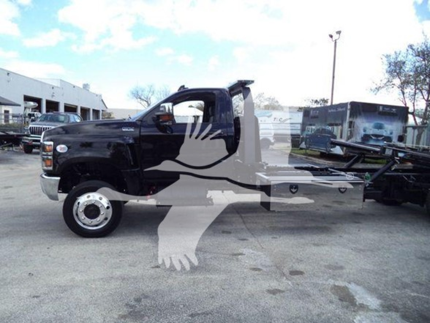 Truck with rollback bed showing side profile of a black cab and equipment on a flatbed, VIN sticker not visible in image.