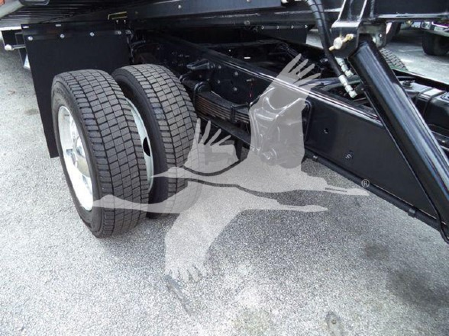 Truck chassis and dual rear tires showing suspension and frame with black metallic components.