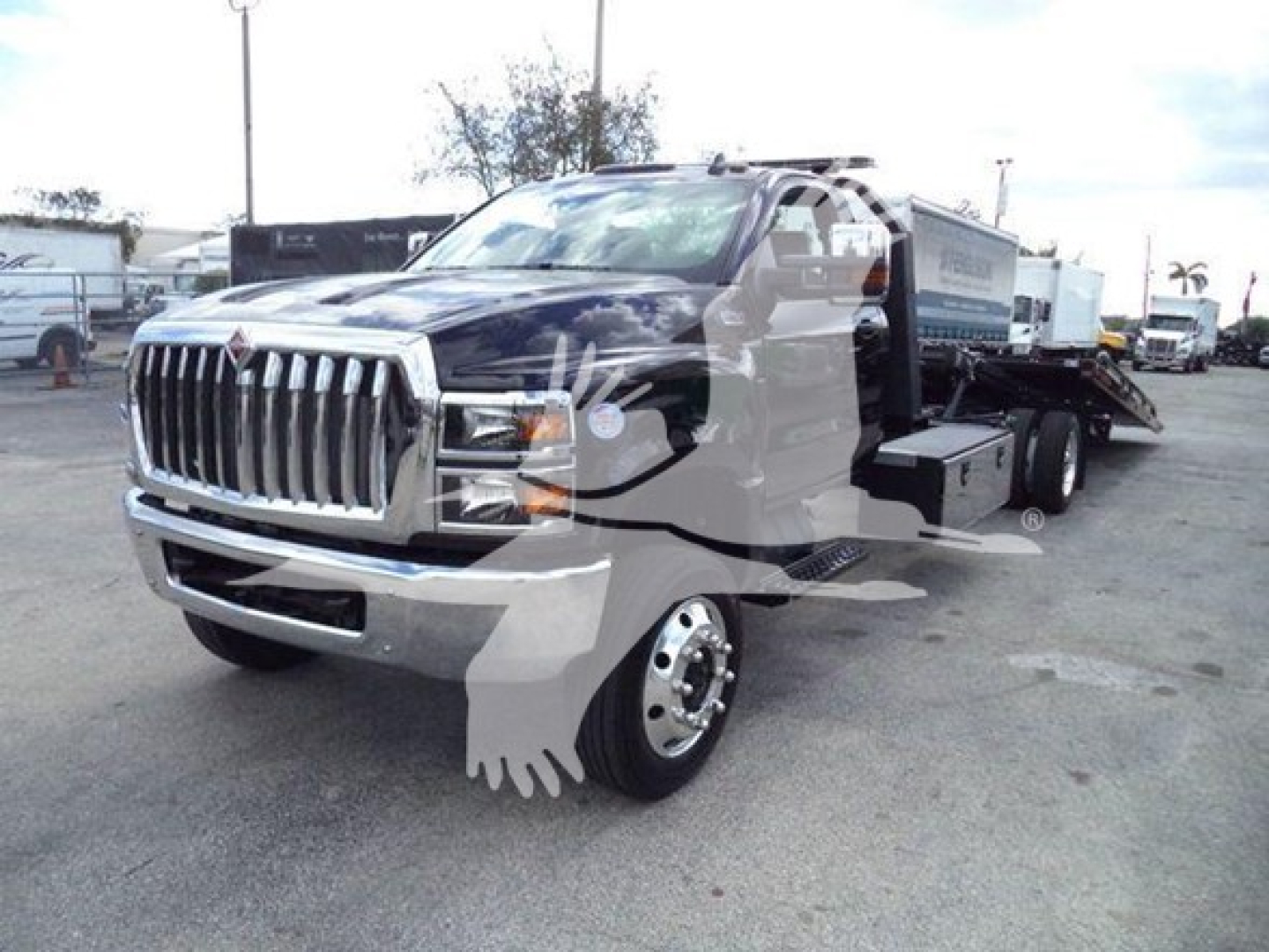 Truck in a lot with front grille, International CV-Series rollback tow truck, visible chrome grille and headlights.