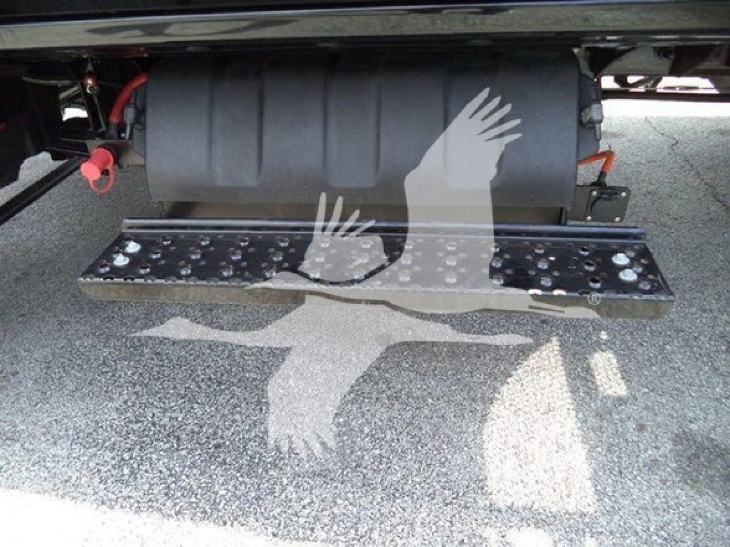 Truck rear with metal steps and black fuel tank; diamond-plate step surface; shadow pattern of birds painted on ground.