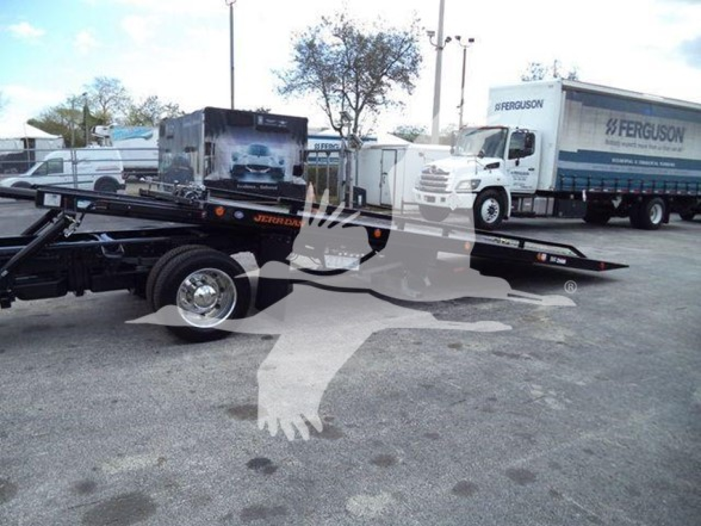 Truck rollback trailer with International CV/CV series chassis and Ferguson truck behind, dealership lot in background.