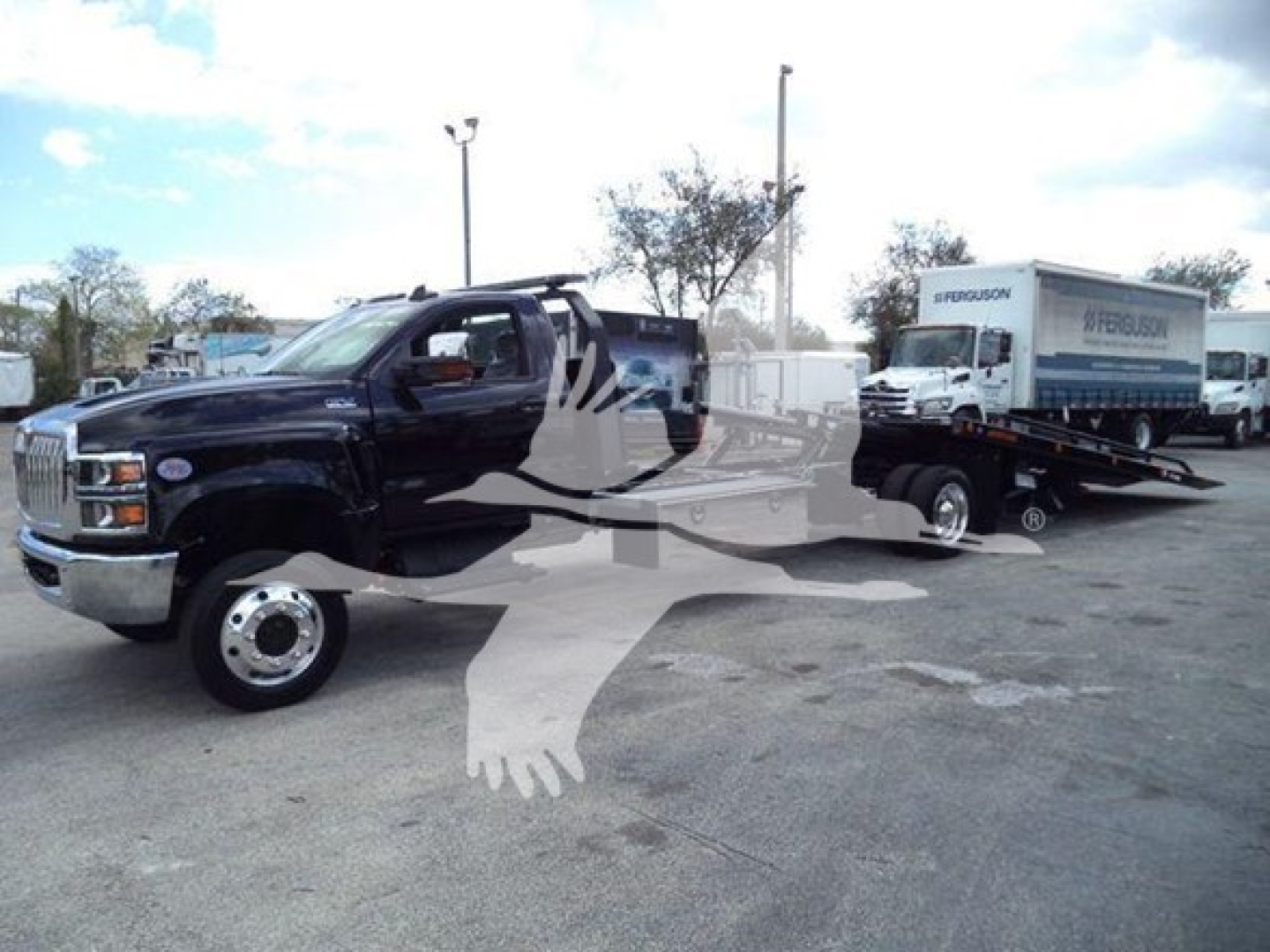 Truck on rollback tow with black cab and white sleeper, attached flatbed with a Ferguson box truck in background; VIN 1HTKTSWK6PH441635 visible in listing.
