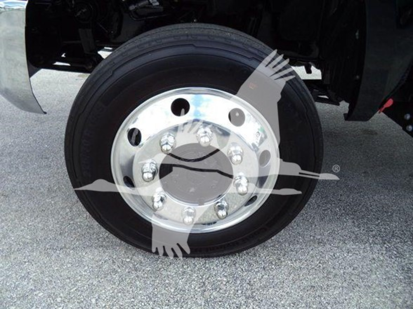 Truck wheel with polished rim and tire, front axle view in a rollback truck, chrome hub with bolts visible