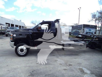 Truck with rollback bed showing side profile of a black cab and equipment on a flatbed, VIN sticker not visible in image.